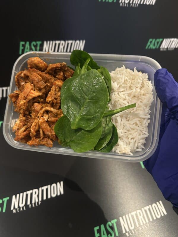 Nutritious meal box with rice, chicken, and spinach for macronutrient balance and muscle support.
