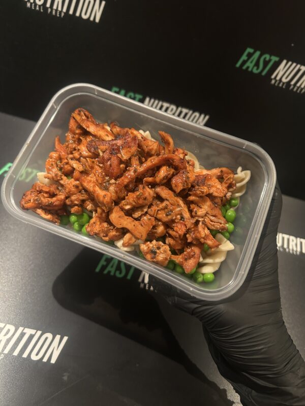 Healthy meal prep with shredded chicken, pasta, and peas for muscle building.